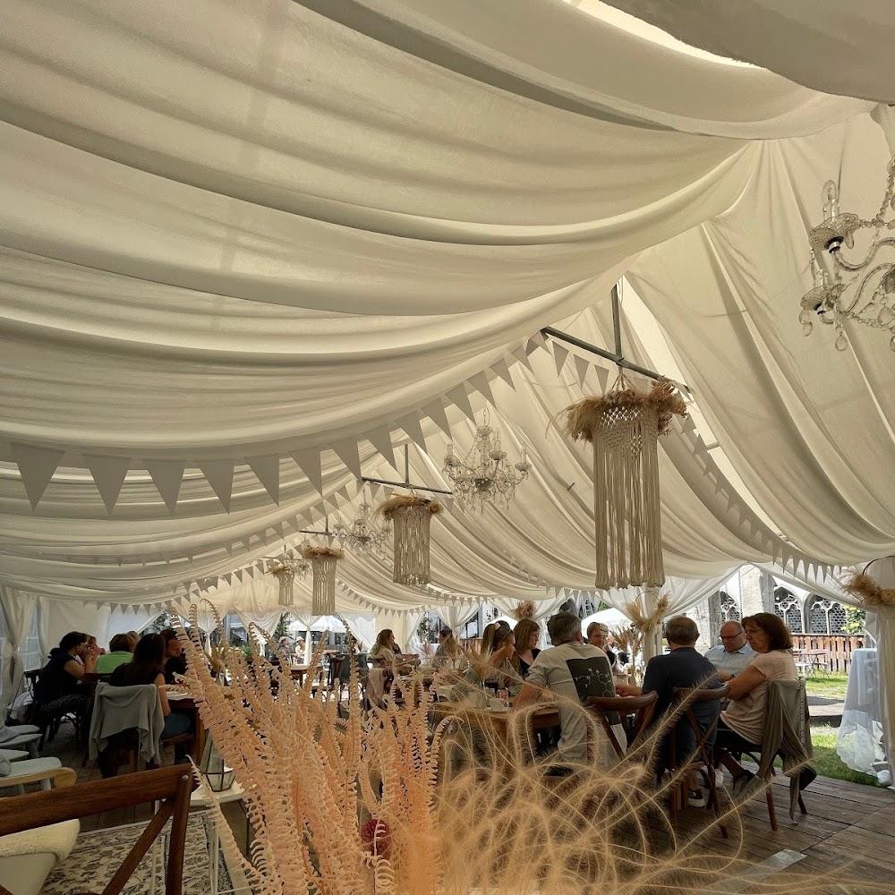 People seated under a white tent with chandeliers.